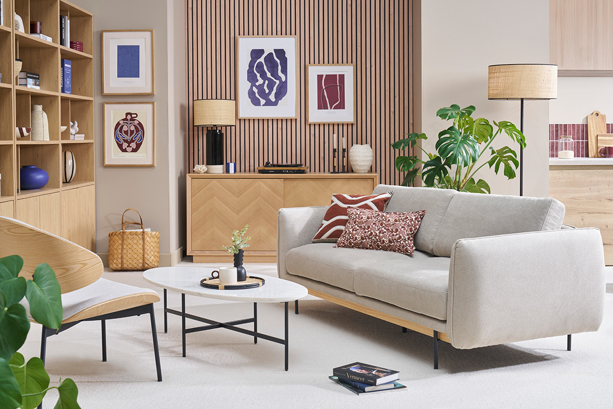 Canap� design 3 places en tissu beige avec coussins, vue de face dans un salon moderne.