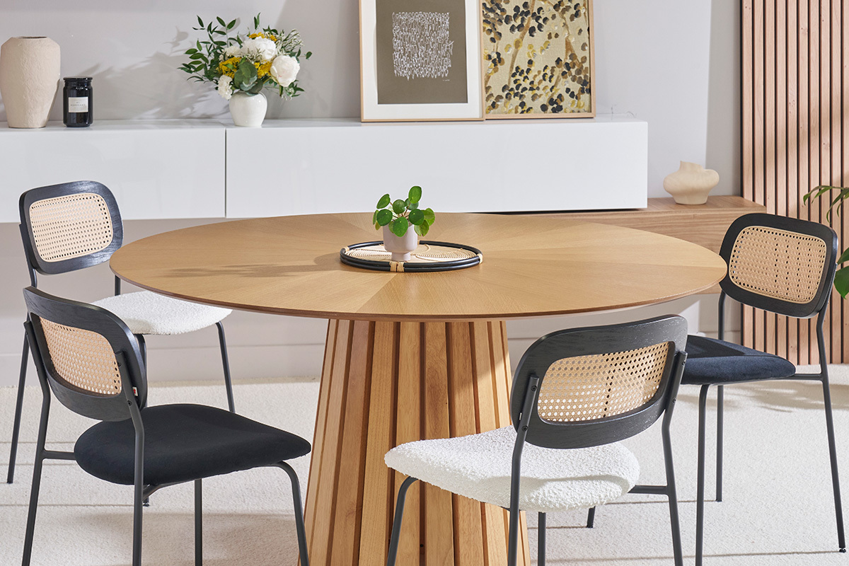 Salle � manger avec des chaises MIRANDA en tissu blanc, m�tal noir et rotin autour d'une table ronde en bois.