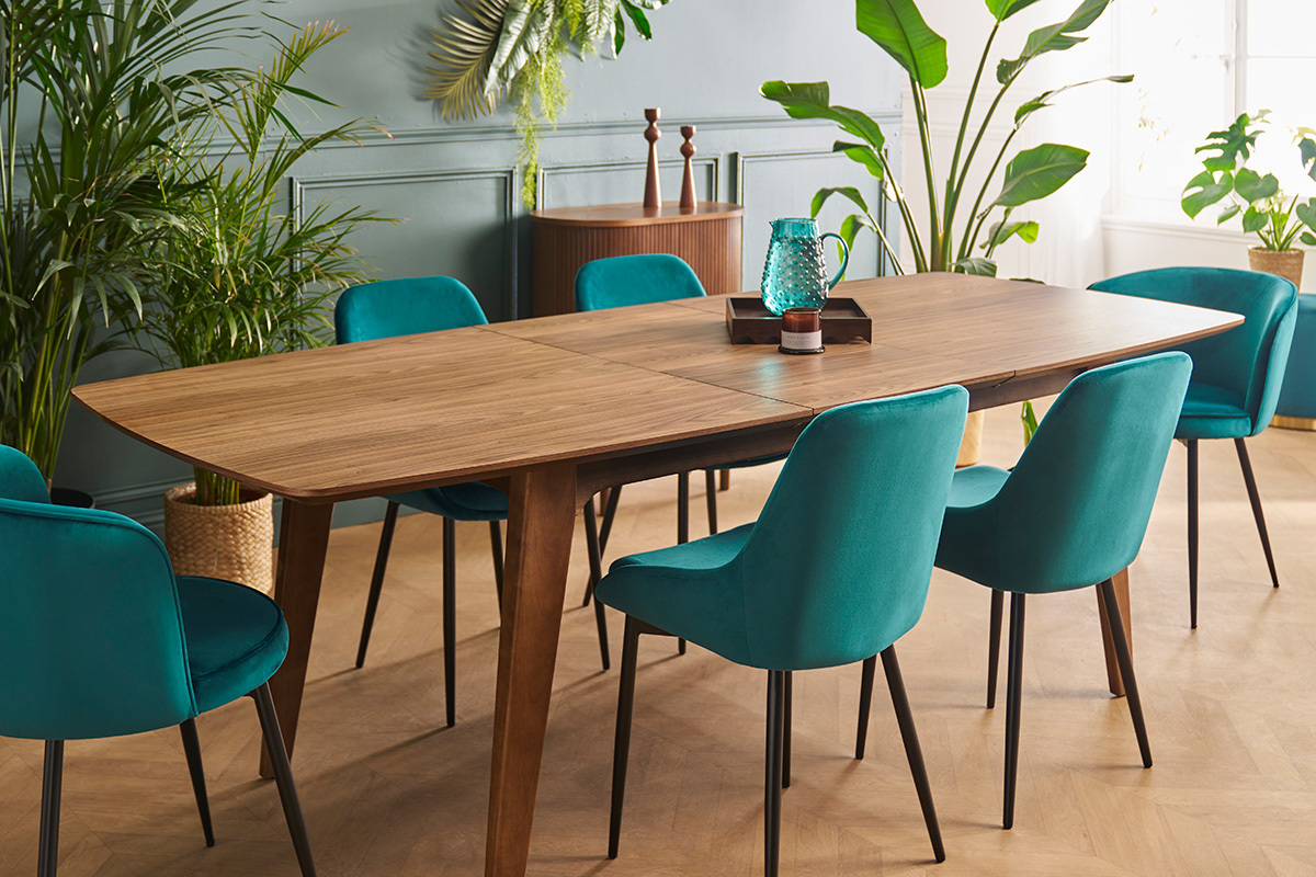 Chaises HOLO en velours bleu p�trole avec pieds en m�tal noir autour d'une table en bois, vue d'ensemble.