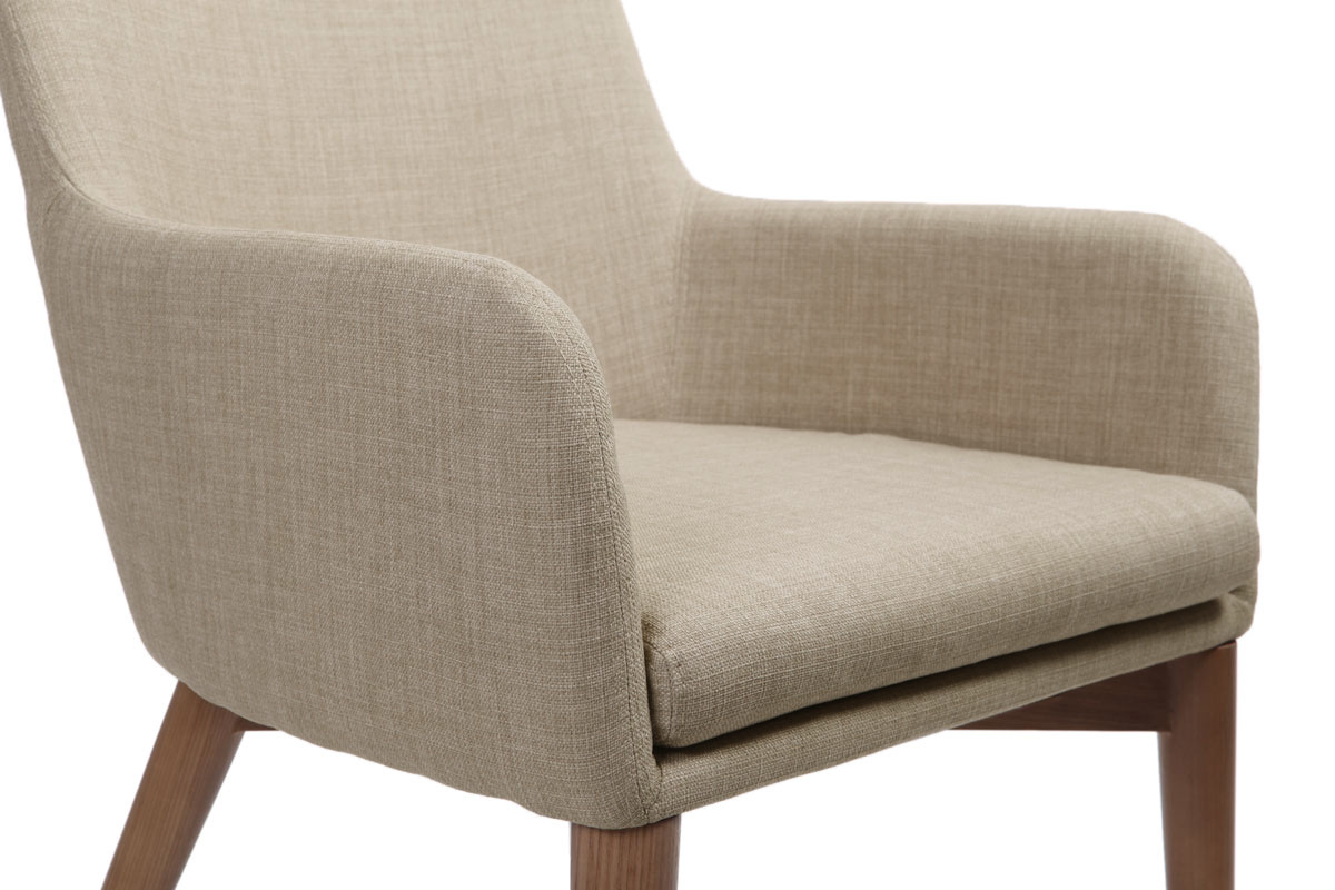 Chaise beige en tissu avec accoudoirs arrondis et pieds en bois fonc�, vue partielle de c�t�.