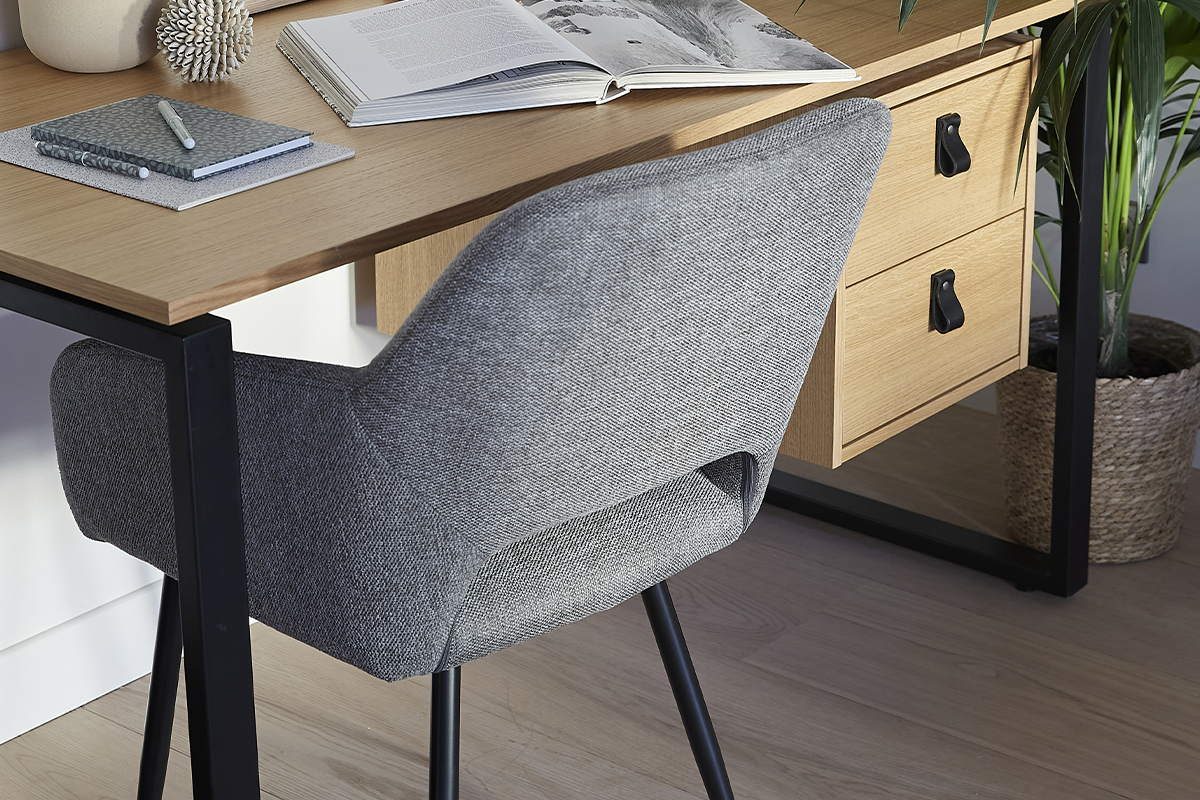 Chaise en tissu gris effet velours, dos vue 3/4, avec bureau en bois.