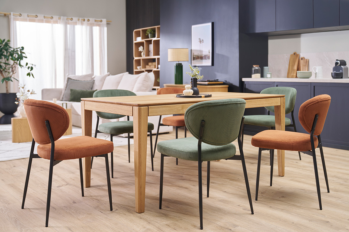Salle � manger moderne avec diff�rentes chaises en velours c�tel� autour d'une table en bois.