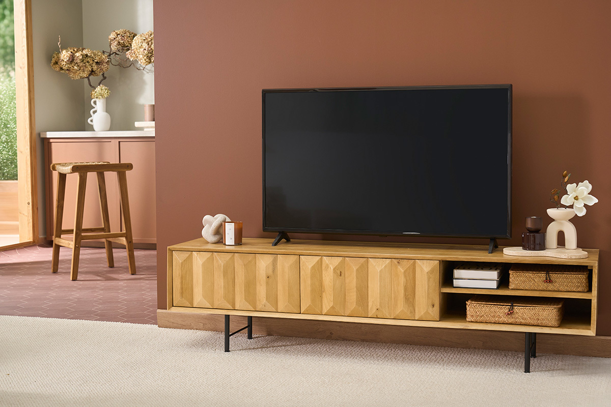 Meuble TV en bois clair manguier massif avec gravures et pi�tement noir, TV pos�e dessus.