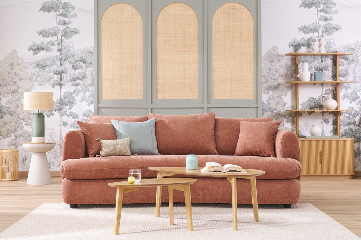 Canap� rose avec table d'appoint en m�tal gr�ge et bois manguier, lampe et �tag�res en arri�re-plan.